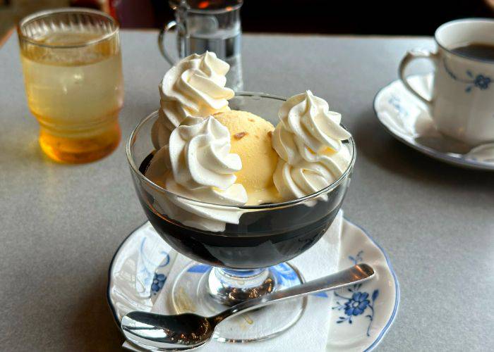 A traditional serving of Kissaten coffee jelly, showing a nostalgic glass dish of coffee jelly, vanilla ice-cream and whipped cream.